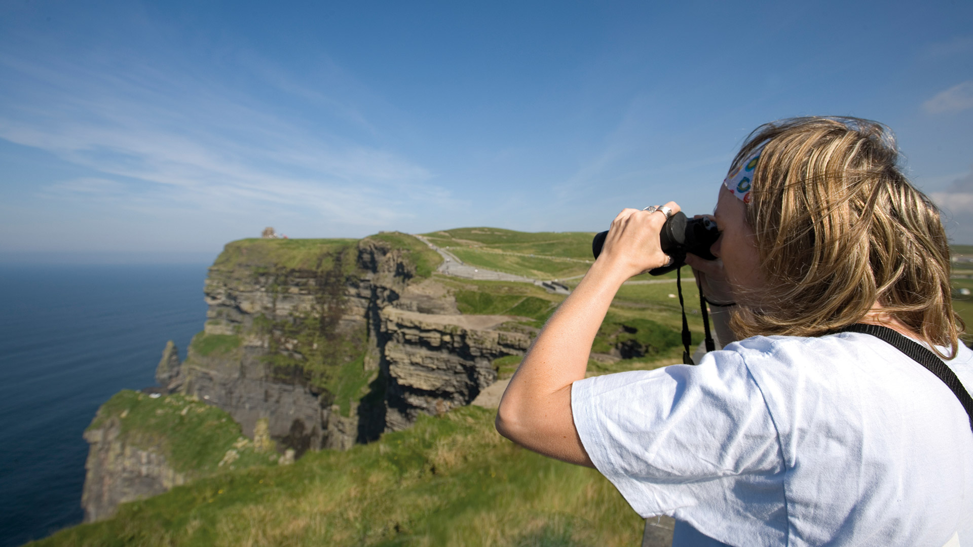 Girl with binoculars looking at the Cliffs
